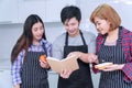 Groups of friends cooking together meal food in the kitchen. Cheerful smiling young man holding book learning cook with his Royalty Free Stock Photo