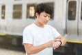 Asian guy looking at watch standing on city street Royalty Free Stock Photo