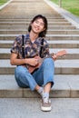 Asian guy smiling and playing acoustic Ukulele guitar sitting on stairs. Royalty Free Stock Photo