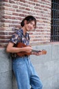 Asian guy smiling and playing acoustic Ukulele guitar. Royalty Free Stock Photo