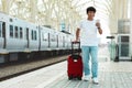 Asian guy traveler using smartphone, standing by train Royalty Free Stock Photo