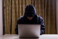 Asian hacker hacking computer network with laptop