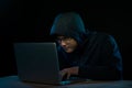 Asian hacker hacking computer network with laptop in dark. Cyber security concept Royalty Free Stock Photo