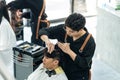 Asian hairdresser barber male cut hair of attractive man in salon shop. Professional hairstylist combing and using scissors give Royalty Free Stock Photo