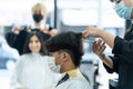 Asian hairdresser barber team wear mask, cut hair of customer in shop. Young man and woman client in modern salon barbershop, Royalty Free Stock Photo