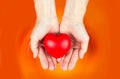 Asian hand hold heart on orange