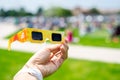 Asian hand wear smart watch holding paper solar eclipse with blurry crowd people watching totality show in Dallas, Texas