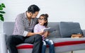 Asian handsome adult warm father and sweet cute little daughter girl sitting on sofa in living room at home, drawing, doing Royalty Free Stock Photo