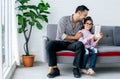 Asian handsome adult warm father and sweet cute little daughter girl sitting on sofa in living room at home, drawing, doing Royalty Free Stock Photo