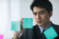 Asian handsome business man wearing formal suit with necktie, writing message of working plan or his creative idea on colorful Royalty Free Stock Photo