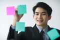 Asian handsome business man wearing formal suit with necktie, writing message of working plan or his creative idea on colorful Royalty Free Stock Photo