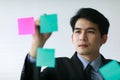 Asian handsome business man wearing formal suit with necktie, writing message of working plan or his creative idea on colorful Royalty Free Stock Photo