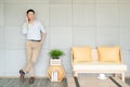 Asian handsome man standing talking telephone in living room with interior completely, sofa table coffee cup.