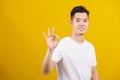 Handsome young man smiling positive holding ok sign gesturing with hand and fingers