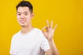 Young man smiling positive holding ok sign gesturing with hand and fingers