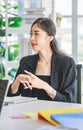 Asian happy cheerful professional successful female businesswoman employee in formal suit sitting smiling holding hands up Royalty Free Stock Photo