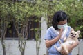 Asian Happy child wear mask and playing puppy dogs. Relationship of Cute little girl and chihuahua dog, hugging together in park. Royalty Free Stock Photo