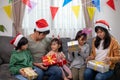 Asian Happy family with daughter in Santa hats gathered together on Christmas time and enjoy gifts box