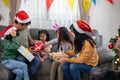 Asian Happy family with daughter in Santa hats gathered together on Christmas time and enjoy gifts box