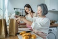 Asian happy family, senior mom and daughter cook food and sale at home. Attractive beautiful girl use phone call to receive order