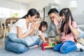 Asian happy family sit on floor, play kid toy together in living room. Attractive parents mother and father spend time with young Royalty Free Stock Photo