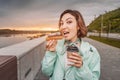 Happy girl eats a fresh French dessert Eclair and drinks coffee. Street food takeaway. Recreation and leisure on the city Royalty Free Stock Photo