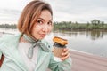 Happy girl eats a fresh French dessert Eclair and drinks coffee. Street food takeaway. Recreation and leisure on the city Royalty Free Stock Photo