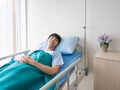 Asian happy patient man smile and healthy fine while resting in bed hospital after see doctor, nurse and visitor encouraged him at Royalty Free Stock Photo