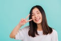 Asian happy portrait beautiful cute young woman teen smile standing wear t-shirt showing finger making v-sign symbol near eye look Royalty Free Stock Photo