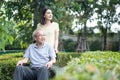 Asian happy Senior retired grandfather enjoy outdoor at green park. Attractive girl daughter pushing elderly father on wheelchair Royalty Free Stock Photo