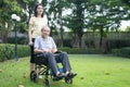 Asian happy Senior retired grandfather enjoy outdoor at green park. Attractive girl daughter pushing elderly father on wheelchair Royalty Free Stock Photo