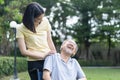 Asian happy Senior retired grandfather enjoy outdoor at green park. Attractive girl daughter pushing elderly father on wheelchair Royalty Free Stock Photo