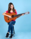 Asian happy singer woman sit on bar chair and sing a song with acoustic guitar