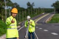 Asian happy surveyor engineers with digital level looking at camera on road construction site, Civil Engineers, Surveyor equipment