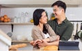 Asian happy young adult couple lover helping together, cooking in cozy home kitchen in morning, preparing breakfast meal, smiling Royalty Free Stock Photo