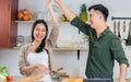 Asian happy young adult couple lover helping together for cooking in cozy home kitchen in morning, preparing meal for breakfast, Royalty Free Stock Photo