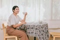 Asian healthy girl teen sitting alone at the table hand hold coffee mug in home smiling for happy single lifestyle Royalty Free Stock Photo