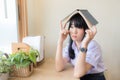 Asian high school girl in iniform looking out the window with book on her head