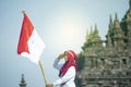 Asian Hijab Holding Indonesian flag with clear blue skyand Plaosan Temple background, Indonesia independence day Royalty Free Stock Photo