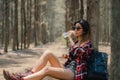 Asian hiker woman trekking in forest. Young happy backpack girl sitting rest drink water from bottle after walking travel nature