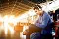 Asian hipster man listening to music at train station with headphones and smartphone. Royalty Free Stock Photo