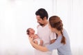 Asian or Hispanic father with beard hold his first child newborn with strong arm, beautiful wife play with baby and try to help Royalty Free Stock Photo