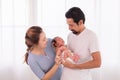 Asian or Hispanic father with beard hold his first child newborn with strong arm, beautiful wife play with baby and try to help Royalty Free Stock Photo