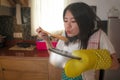 Asian home cook girl lifestyle portrait . Young happy and beautiful Chinese woman in kitchen apron and glove holding cooking pot Royalty Free Stock Photo