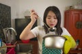 Asian home cook girl lifestyle portrait . Young happy and beautiful Chinese woman in kitchen apron and glove holding cooking pot Royalty Free Stock Photo