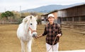 Asian horsewoman training white horse in outdoor riding arena