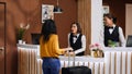 Asian hotel staff greeting customer at front desk entrance Royalty Free Stock Photo