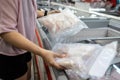 Asian housewife chooses packed frozen seafood compare the size purchases frozen cut fish in freezer shopping in the grocery store