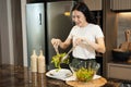 Asian housewife preparing fresh vegetables to make salad at home kitchen counter Royalty Free Stock Photo