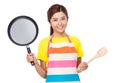 Asian Housewife raised up with frying pan and wooden ladle Royalty Free Stock Photo